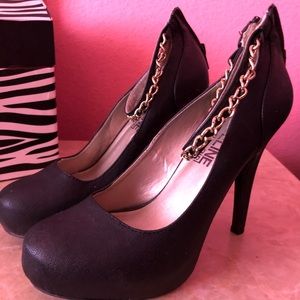 Black platform heels with gold chain ankle wrap.